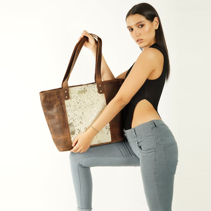 Model posing with a trendy leather tote bag in a studio setting.