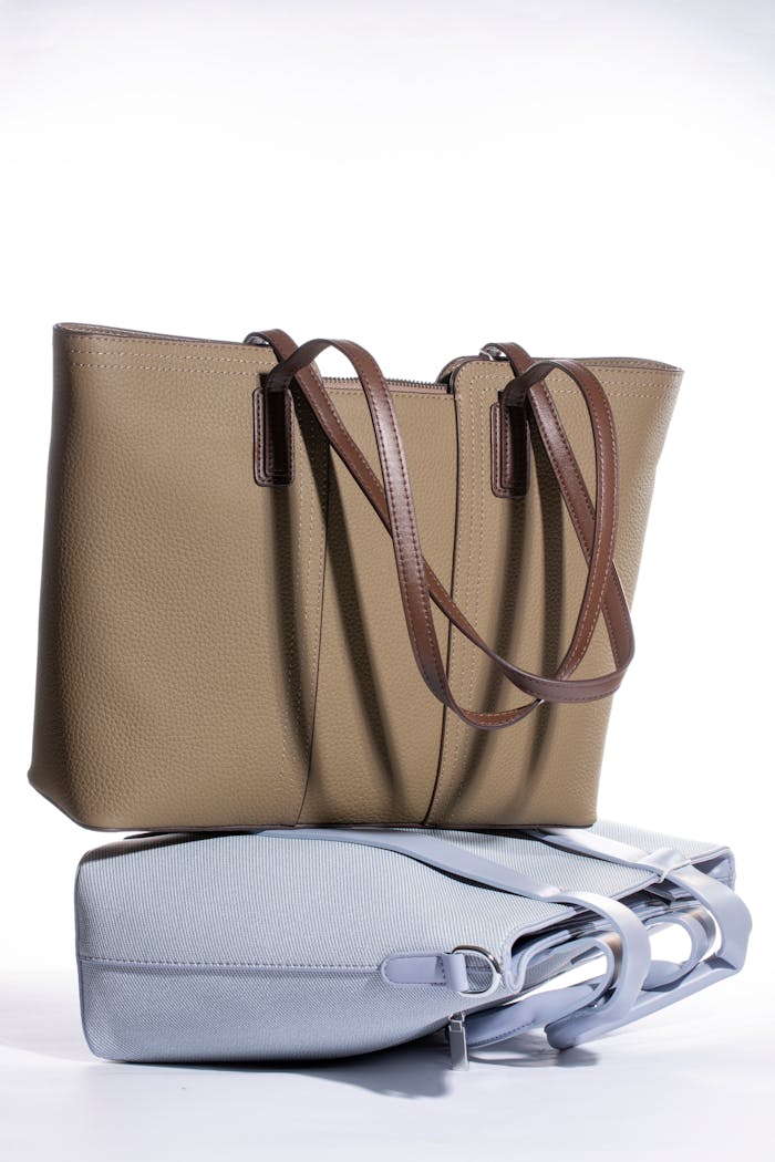 Minimalist display of elegant leather handbags in contrasting beige and light blue tones.